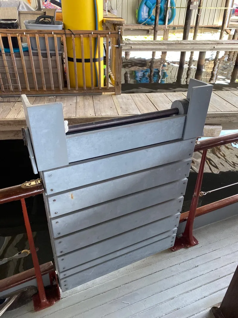 Slide: The Image of 1928 Elco Flat Top boat docked with visible metal gate and wooden deck. - 18