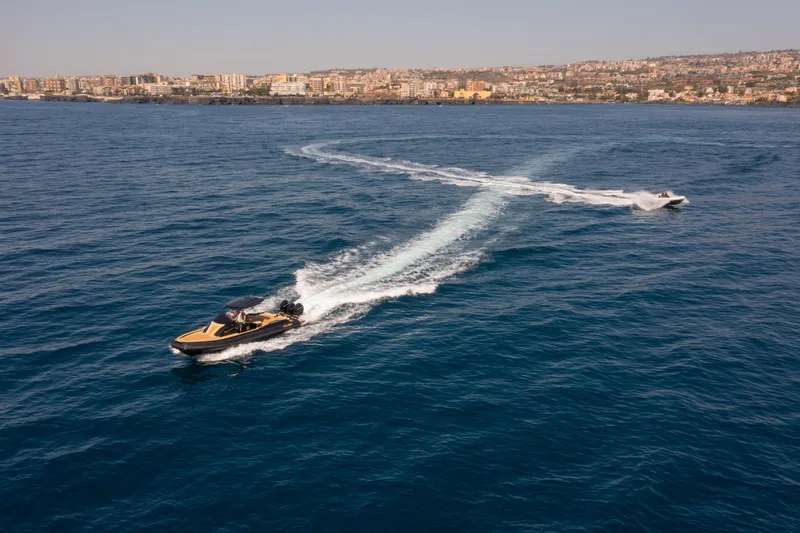 Slide: The Image of 2025 SPX RIB 38 Sport boat cruising on open sea near coastal city. - 14