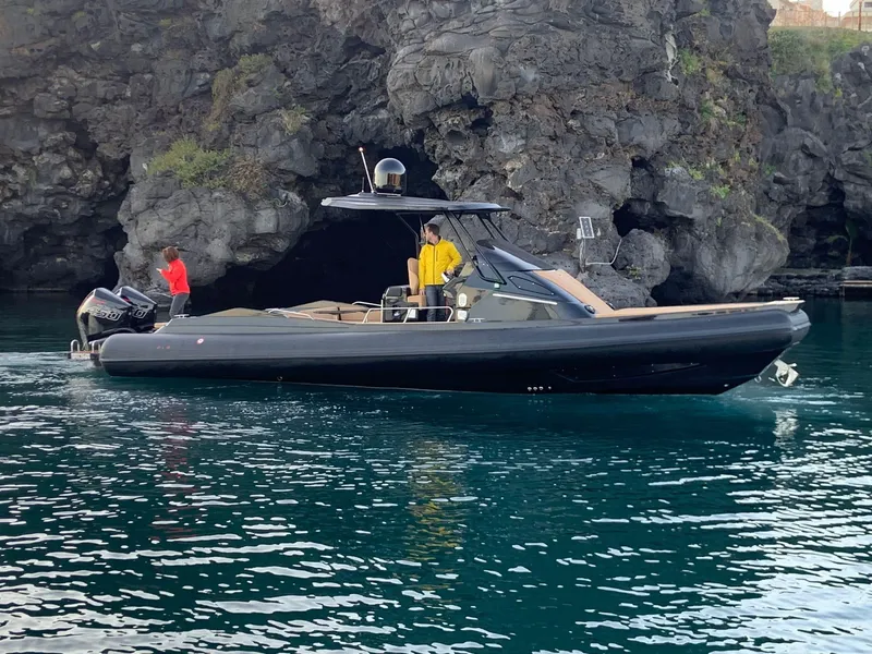 Slide: The Image of 2025 SPX RIB 38 Sport boat near rocky shoreline with two people onboard. - 5