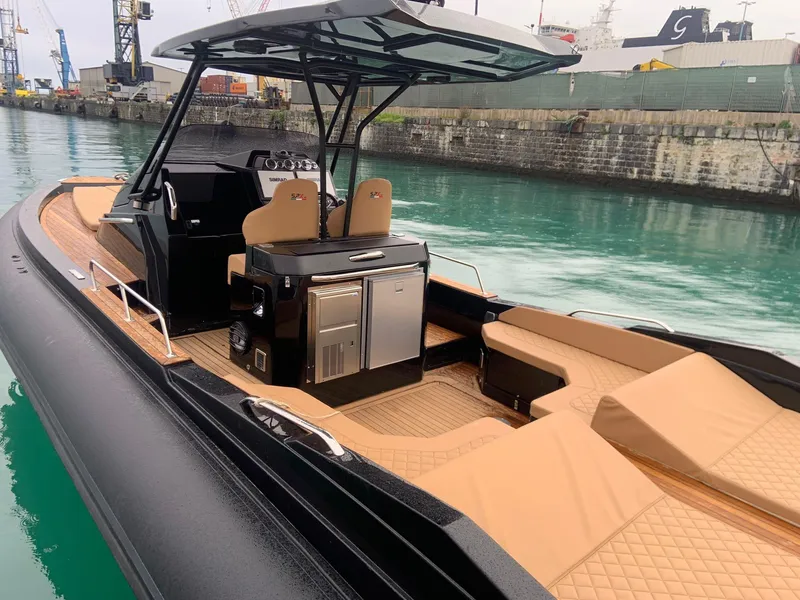 Slide: The Image of 2025 SPX RIB 38 Sport boat with tan seating and black exterior in a marina. - 6