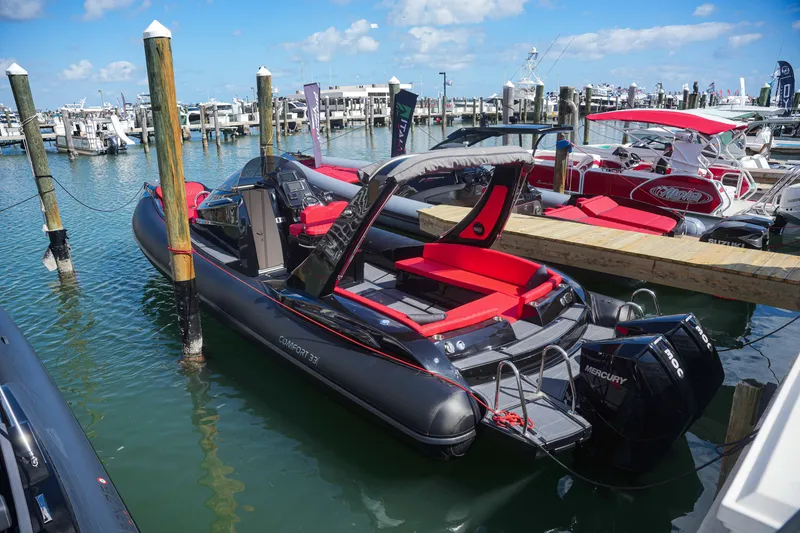 Slide: The Image of 2025 Sea Prop COMFORT 33 boat docked at marina with red seating and Mercury outboard motor. - 4