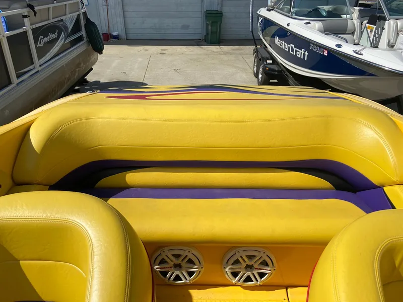 Slide: The Image of 2001 Baja H2X boat with yellow and purple interior, docked near other boats. - 24