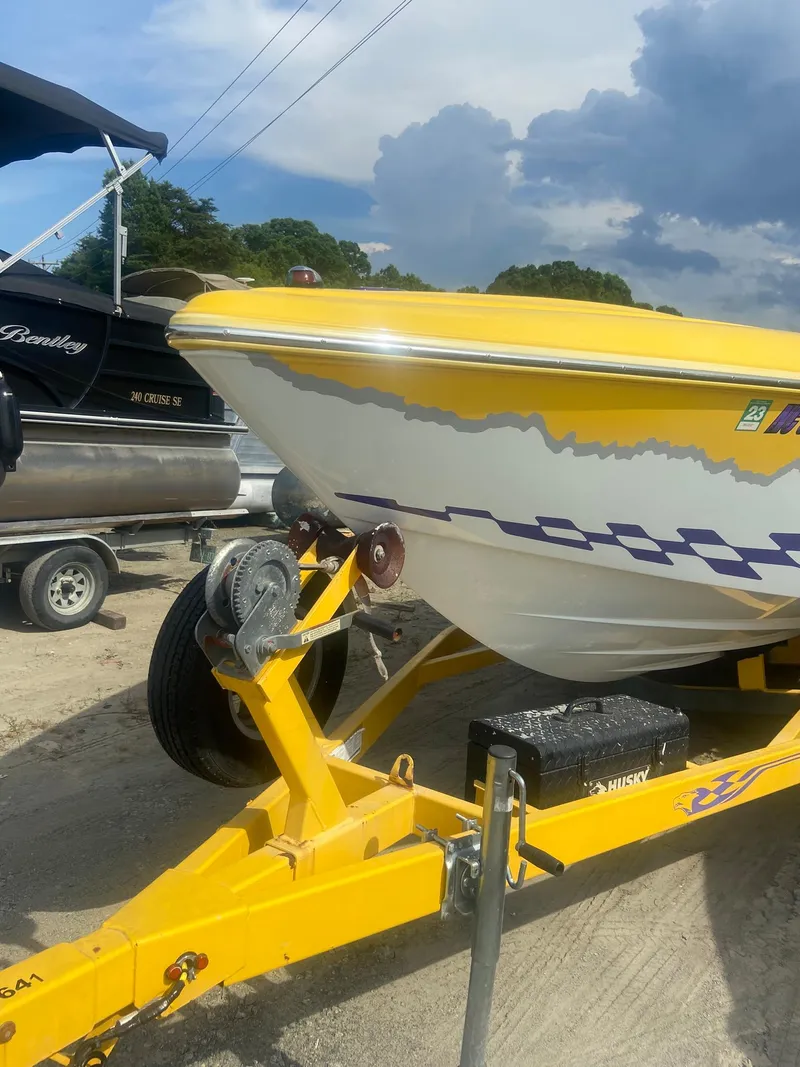 Slide: The Image of 2001 Baja H2X boat on a yellow trailer, parked outdoors. - 7