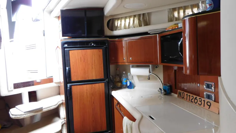 Slide: The Image of 2002 Sea Ray 380 Sundancer interior with kitchenette, featuring wood cabinets and modern appliances. - 38