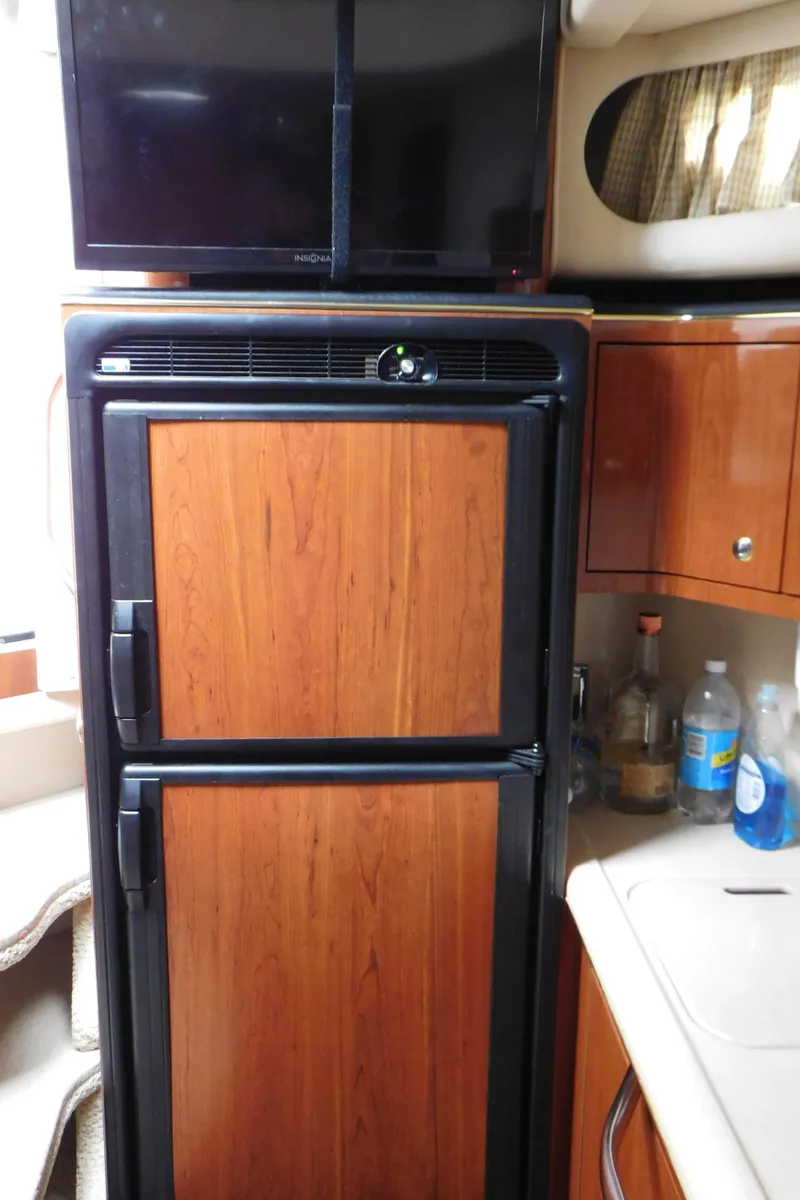 Slide: The Image of 2002 Sea Ray 380 Sundancer interior with wood-paneled fridge and TV. - 41