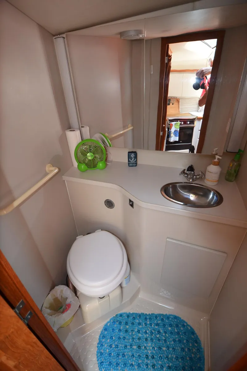 Slide: The Image of 1991 Carver 33 Aft Cabin bathroom with sink, toilet, and blue rug. - 31