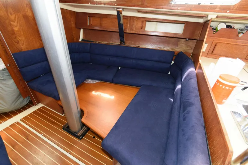 Slide: The Image of Interior of 1987 Pearson 36-2 sailboat with blue cushioned seating and wooden table. - 9
