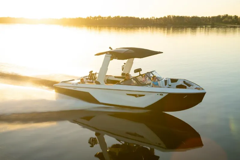 Slide: The Image of 2023 Nautique Super Air Nautique S25 boat cruising on a serene lake at sunset. - 12