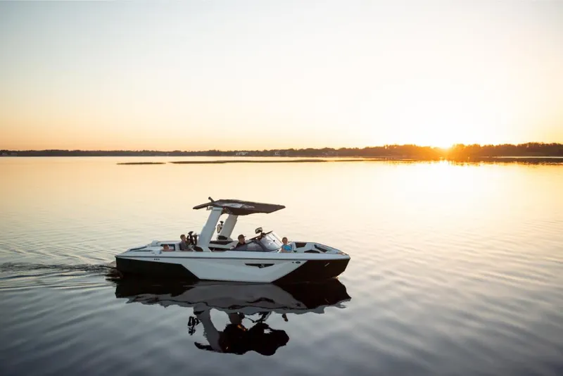 Slide: The Image of 2023 Nautique Super Air Nautique S25 boat cruising at sunset on calm water. - 14