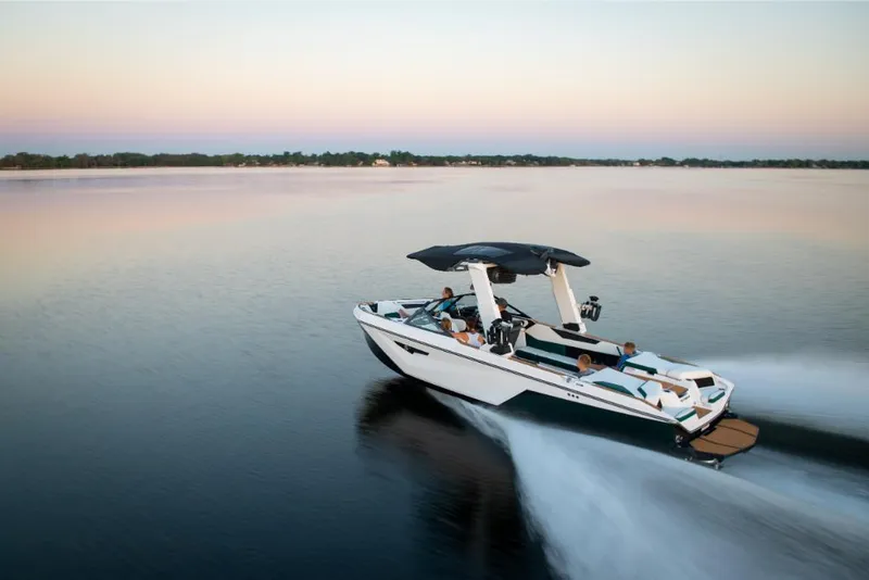 Slide: The Image of 2023 Nautique Super Air Nautique S25 speeding on a calm lake at sunset. - 19