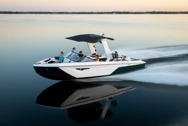 Slide: The Image of 2023 Nautique Super Air Nautique S25 speedboat cruising on calm water at sunset. - 23