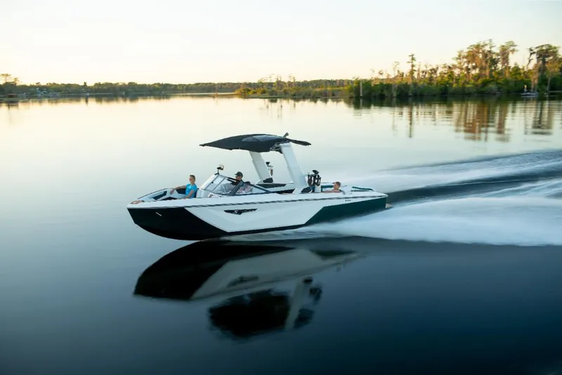 Slide: The Image of 2023 Nautique Super Air Nautique S25 speeding on a calm lake at sunset. - 24