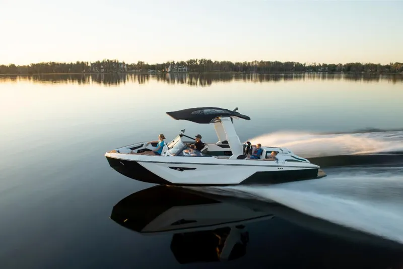 Slide: The Image of 2023 Nautique Super Air Nautique S25 cruising on a calm lake at sunset. - 25