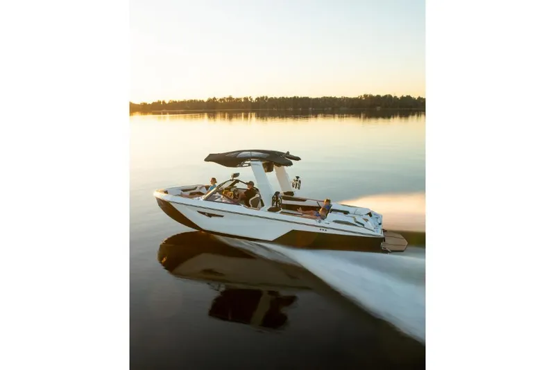 Slide: The Image of 2023 Nautique Super Air Nautique S25 boat cruising on a calm lake at sunset. - 28