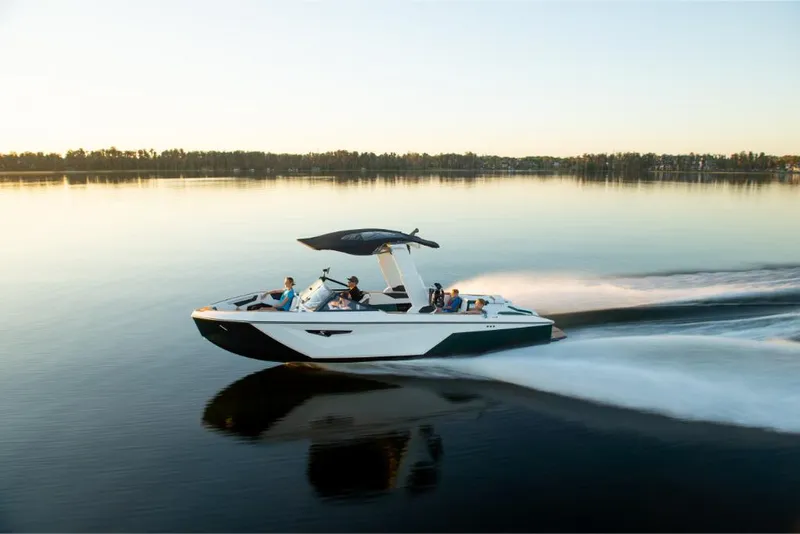 Slide: The Image of 2023 Nautique Super Air Nautique S25 cruising on a calm lake at sunset. - 30