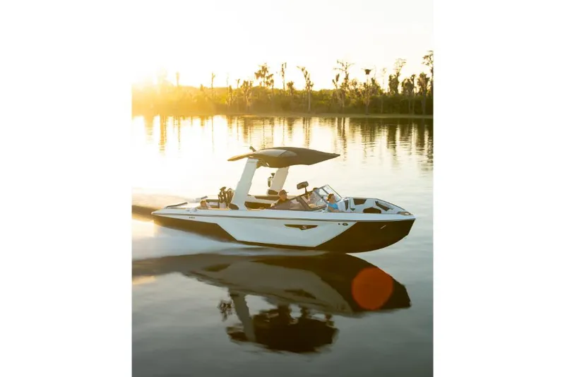 Slide: The Image of 2023 Nautique Super Air Nautique S25 boat cruising on a serene lake at sunset. - 38