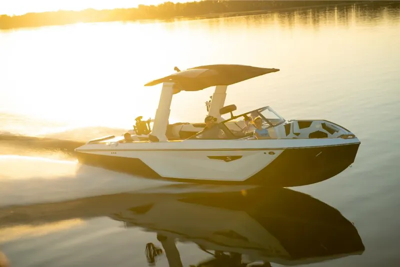 Slide: The Image of 2023 Nautique Super Air Nautique S25 boat cruising on a serene lake at sunset. - 43