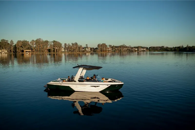 Slide: The Image of 2023 Nautique Super Air Nautique S25 on a calm lake with passengers. - 8