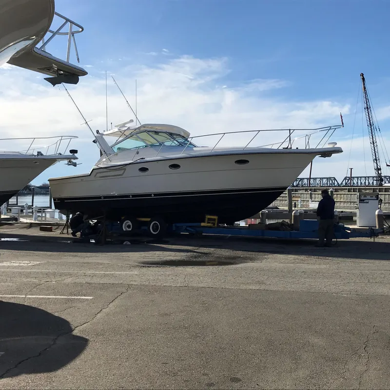 Slide: The Image of 1997 Tiara Yachts 3700 Open on dry dock, marina background, clear sky. - 8