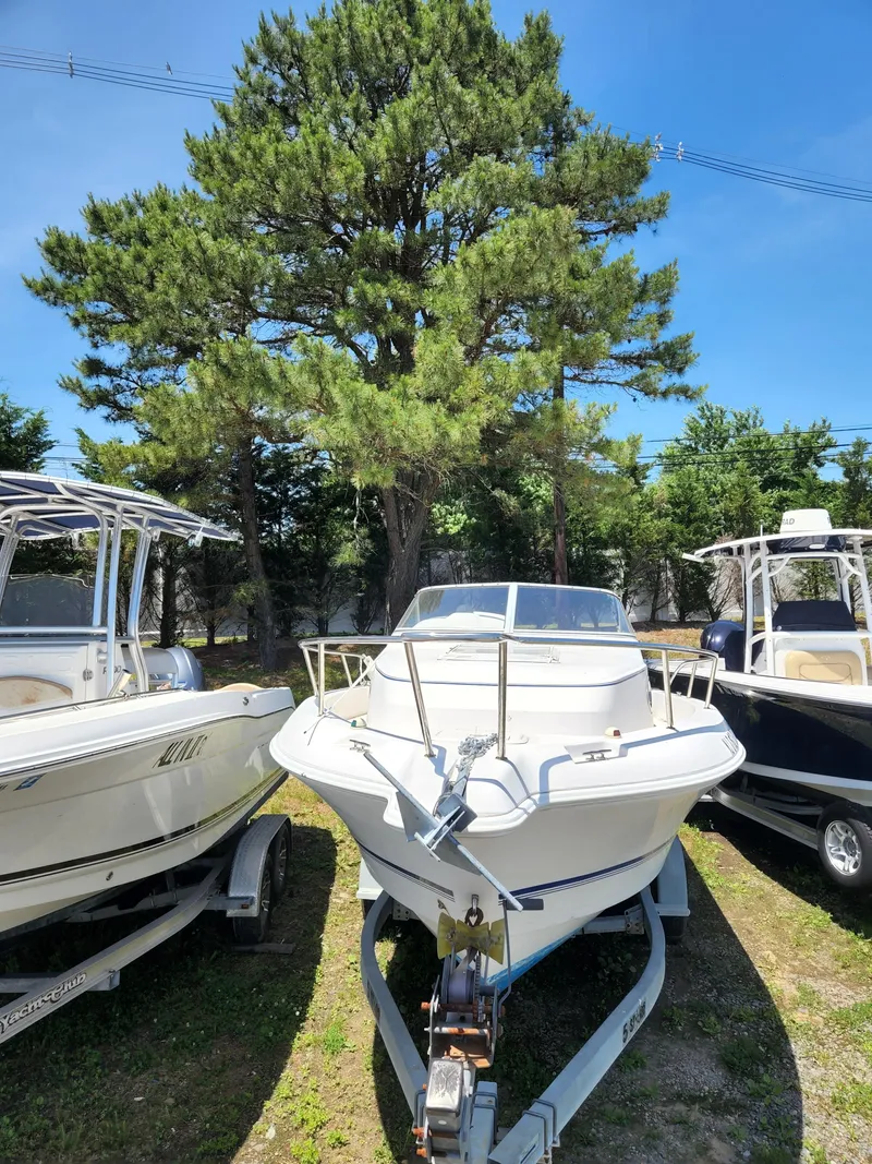 Slide: The Image of 2006 Pro-Line 23 Walk boat on trailer, parked between two other boats. - 11