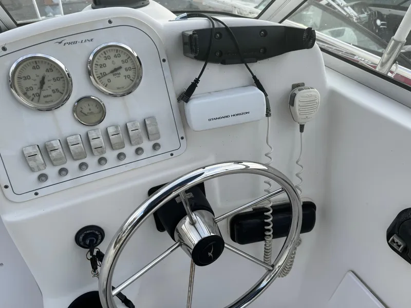 Slide: The Image of 2006 Pro-Line 23 Walk boat dashboard with steering wheel, gauges, and marine radio. - 14