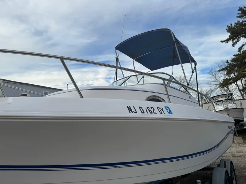 Slide: The Image of 2006 Pro-Line 23 Walk boat with blue canopy, docked on trailer. - 16