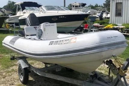 Slide: The Image of 1995 Novurania Tender boat on trailer, parked outdoors near other boats. - 2