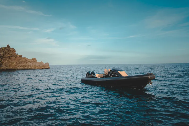 Slide: The Image of 2025 SPX RIB 32 Dinette boat on calm sea near rocky coastline. - 14