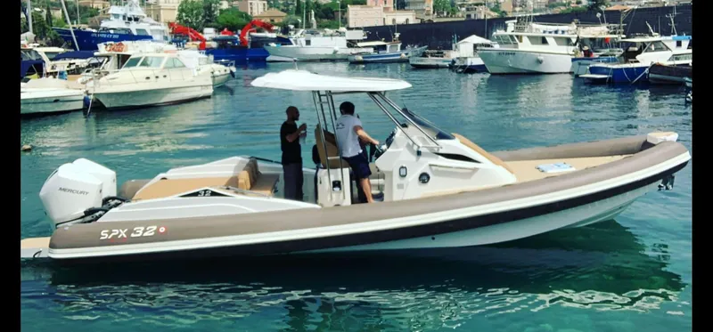 Slide: The Image of 2025 SPX RIB 32 Sport boat docked in a marina with people onboard. - 2