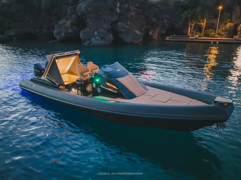 Slide: The Image of 2025 SPX RIB 32 Dinette boat illuminated on serene water at dusk. - 5