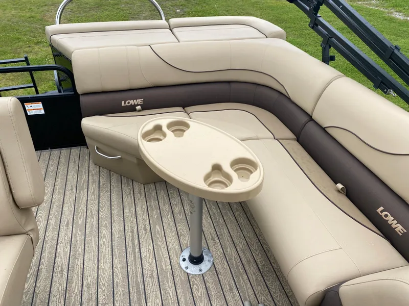 Slide: The Image of 2020 Lowe SS 190 Pontoon boat interior with beige and brown seating and cup holder table. - 7