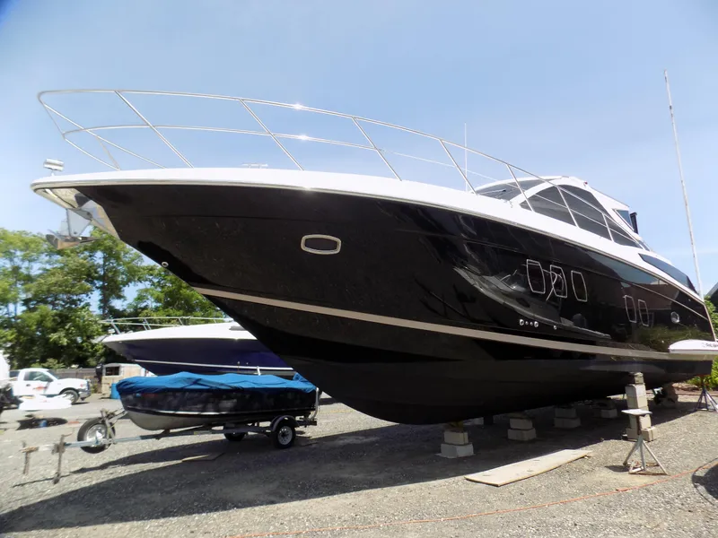 Slide: The Image of 2012 Regal 52 Sport Coupe yacht on dry dock, sleek black hull, sunny day. - 2