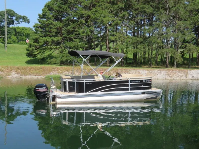The Image of 2016 Harris FloteBote Cruisers CX200 pontoon boat on a calm lake with trees in the background. - 0