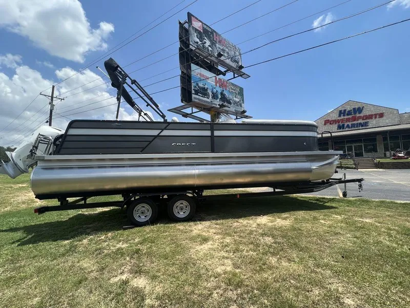 Slide: The Image of 2022 Crest Classic DLX 240 SLSC pontoon boat on trailer outside marine dealership. - 7