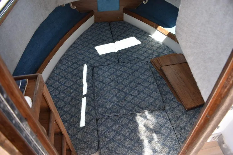 Slide: The Image of 1987 Grady-White Offshore 24 cabin interior with blue patterned cushions and wooden accents. - 12