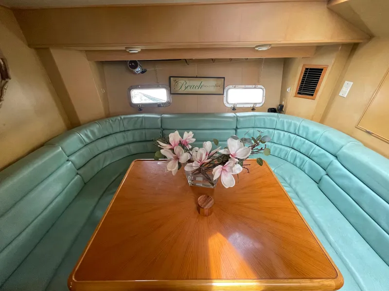 Slide: The Image of 1989 Hi-Star 55 Pilothouse interior with teal seating and wooden table, featuring floral centerpiece. - 15