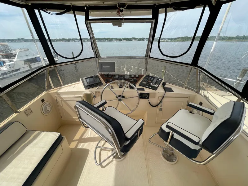 Slide: The Image of 1989 Hi-Star 55 Pilothouse helm with dual seats, steering wheel, and navigation equipment, overlooking water. - 2