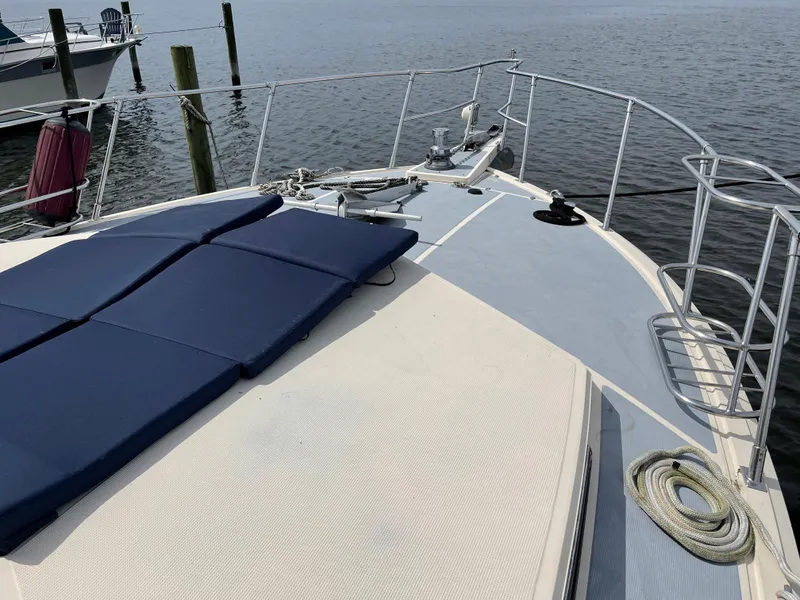 Slide: The Image of 1989 Hi-Star 55 Pilothouse yacht deck with blue cushions and railing, docked by the water. - 26