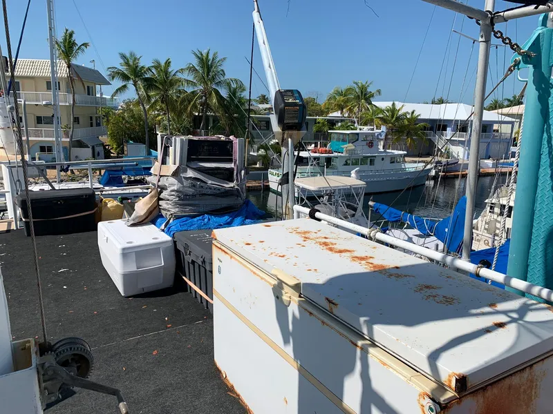 Slide: The Image of 1970 Custom Dive Vessel docked, with equipment and storage boxes on deck. - 43
