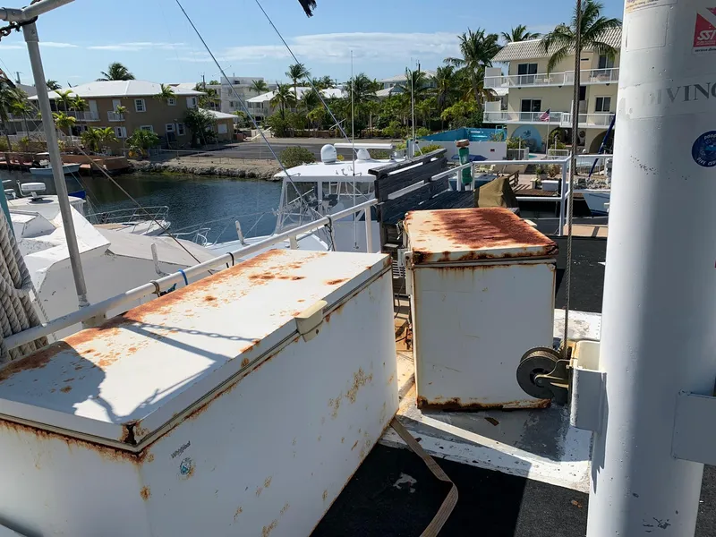 Slide: The Image of Rusty storage boxes on a 1970 Custom Dive Vessel docked near waterfront homes. - 44