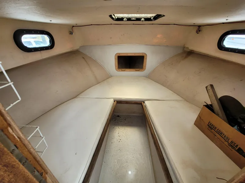 Slide: The Image of Interior cabin of a 1989 C-Hawk 29 boat with white cushions and small windows. - 10