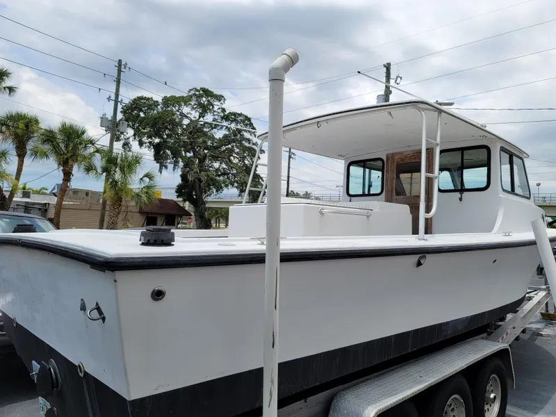 Slide: The Image of 1989 C-Hawk 29 boat on trailer, white exterior, docked outdoors. - 14
