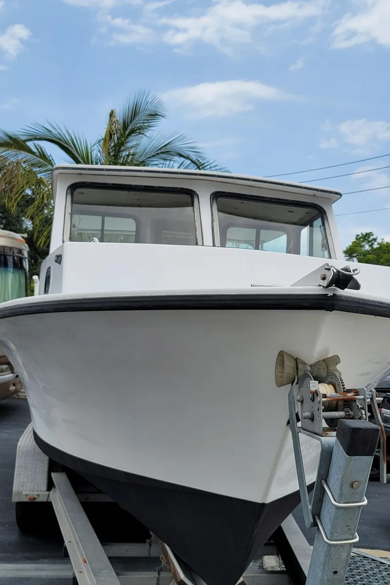 Slide: The Image of 1989 C-Hawk 29 boat on trailer, front view, under clear sky. - 19