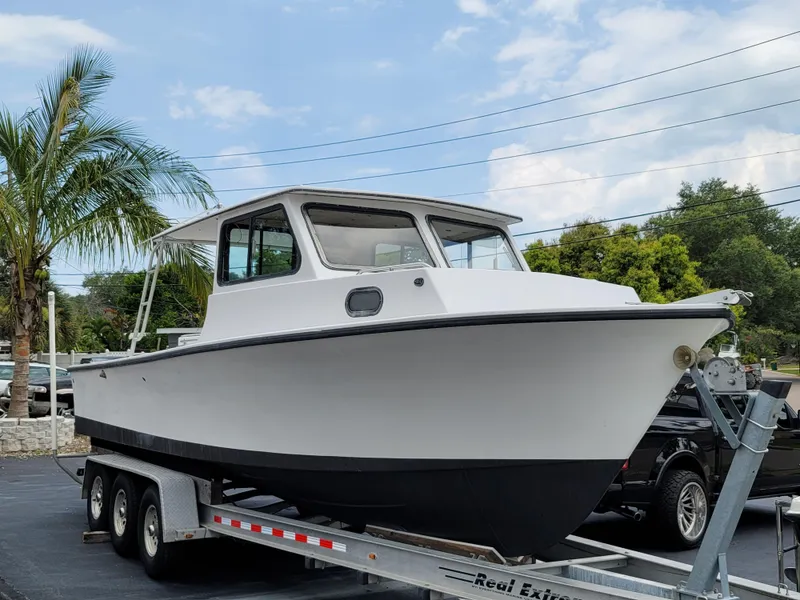 Slide: The Image of 1989 C-Hawk 29 boat on a trailer, parked outdoors with palm trees in the background. - 3