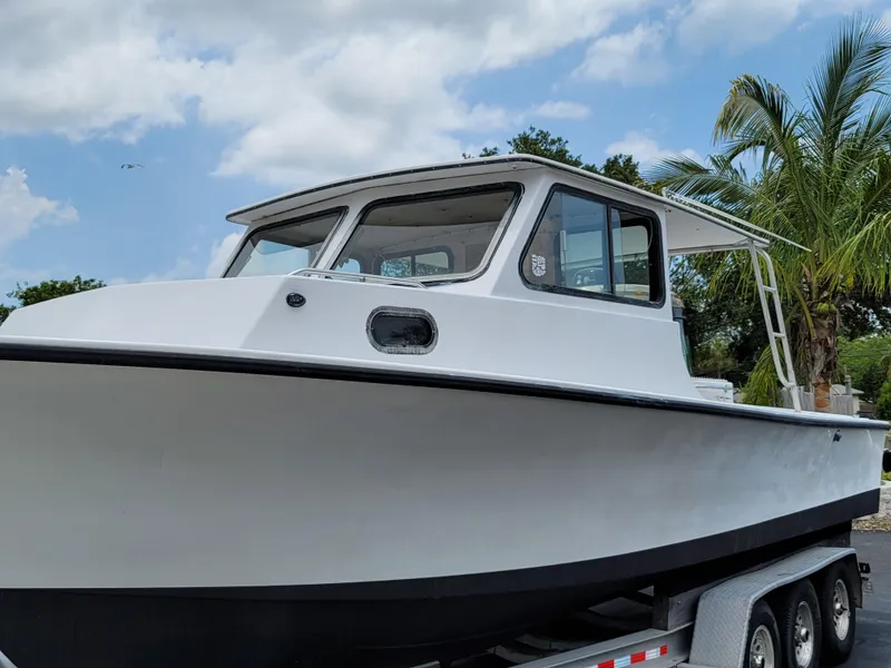 Slide: The Image of 1989 C-Hawk 29 boat on trailer, white hull, cabin, palm trees, blue sky. - 4