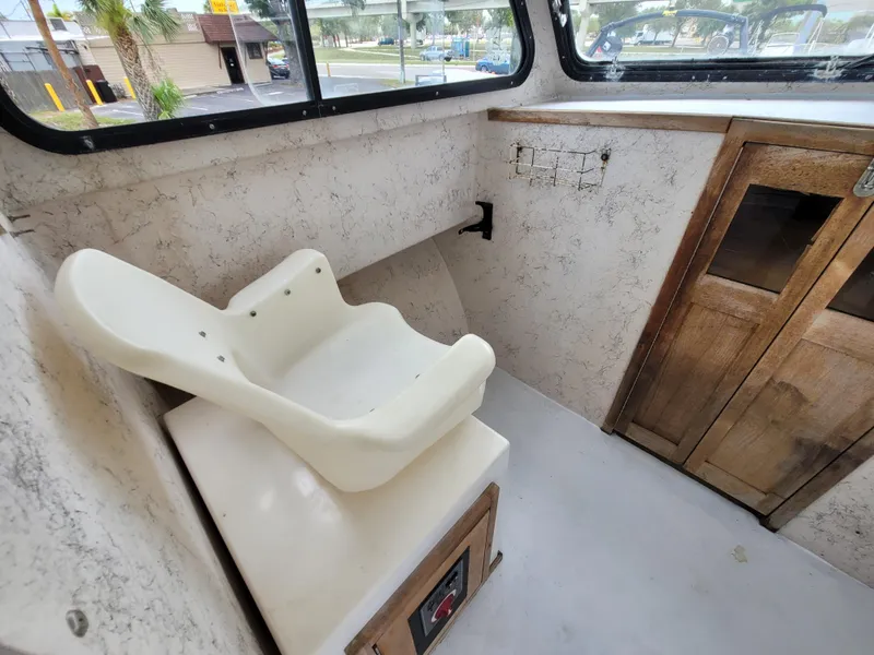 Slide: The Image of 1989 C-Hawk 29 interior with white seat and wooden cabinets. - 9