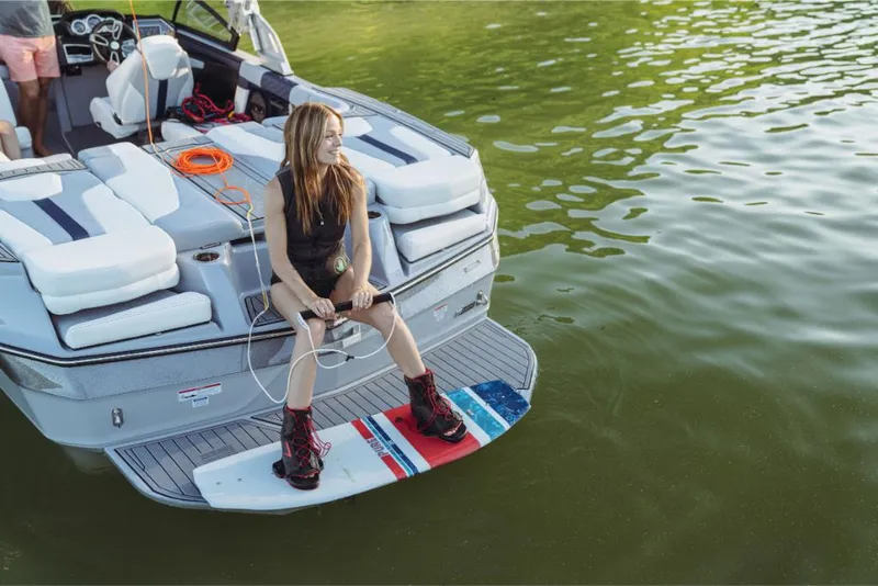 Slide: The Image of 2023 MasterCraft XT22 T boat with a woman preparing to wakeboard on a lake. - 10