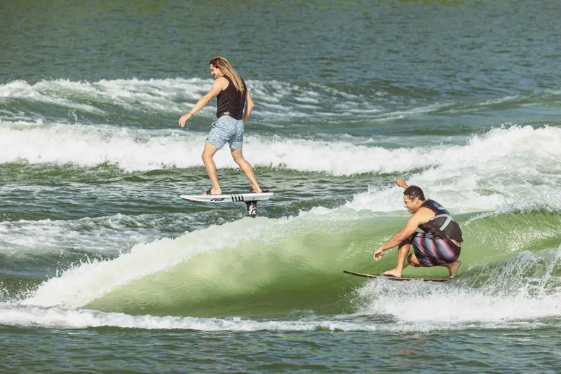 Slide: The Image of Two people wake surfing behind a 2023 MasterCraft XT22 T boat. - 12