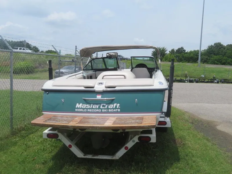 Slide: The Image of 1997 MasterCraft PT205 ski boat, rear view, parked on grass near a fence. - 6