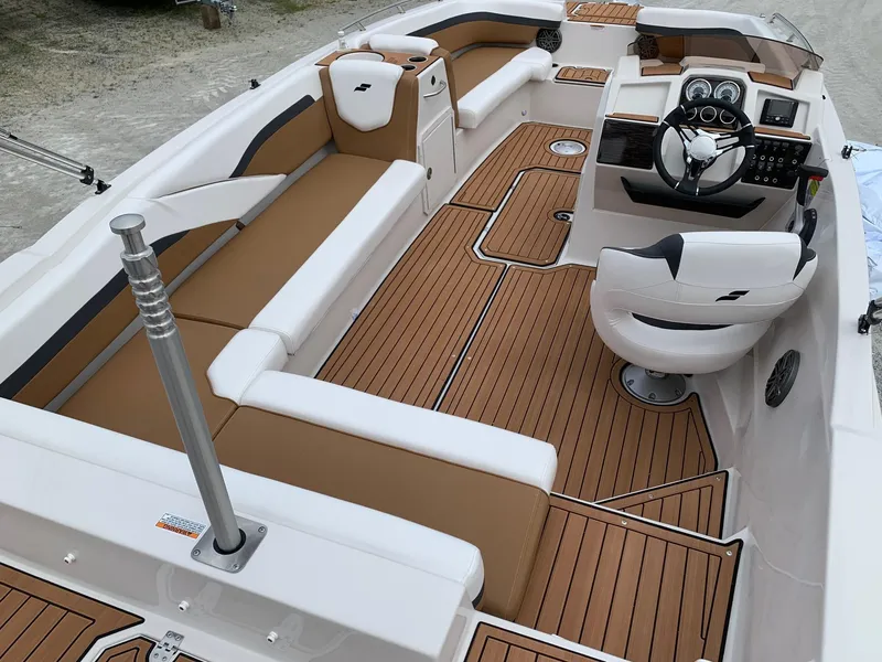 Slide: The Image of 2024 Starcraft SVX 211 boat interior with tan and white seating, modern dashboard, and wood-like flooring. - 12